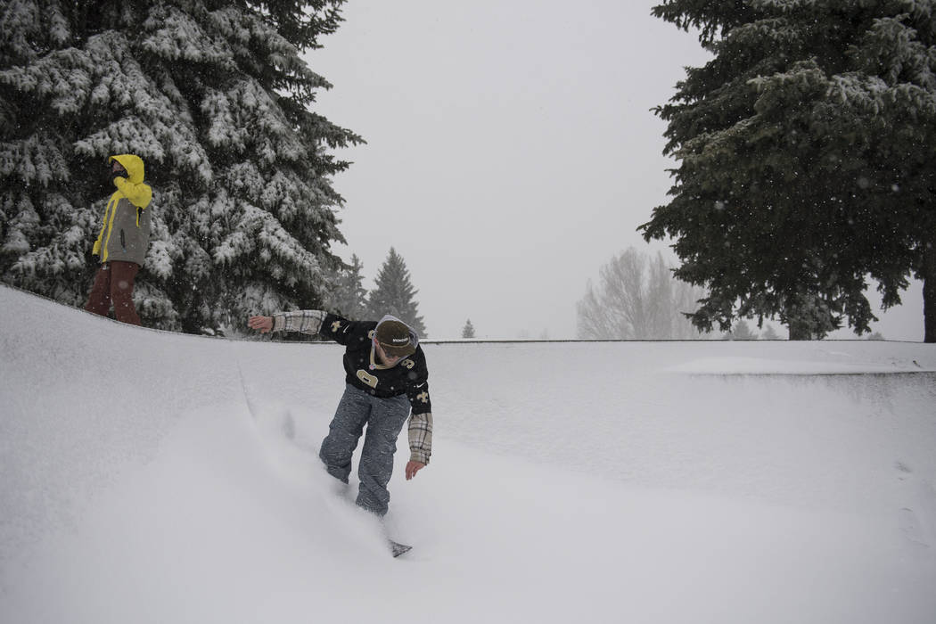 Bobby Larson drops into the bowl on a snowboard in Edora Park on Wednesday, March 13, 2019, in Fort Collins, Colo. A winter storm hit the western U.S., with blizzard conditions expected to engulf ...