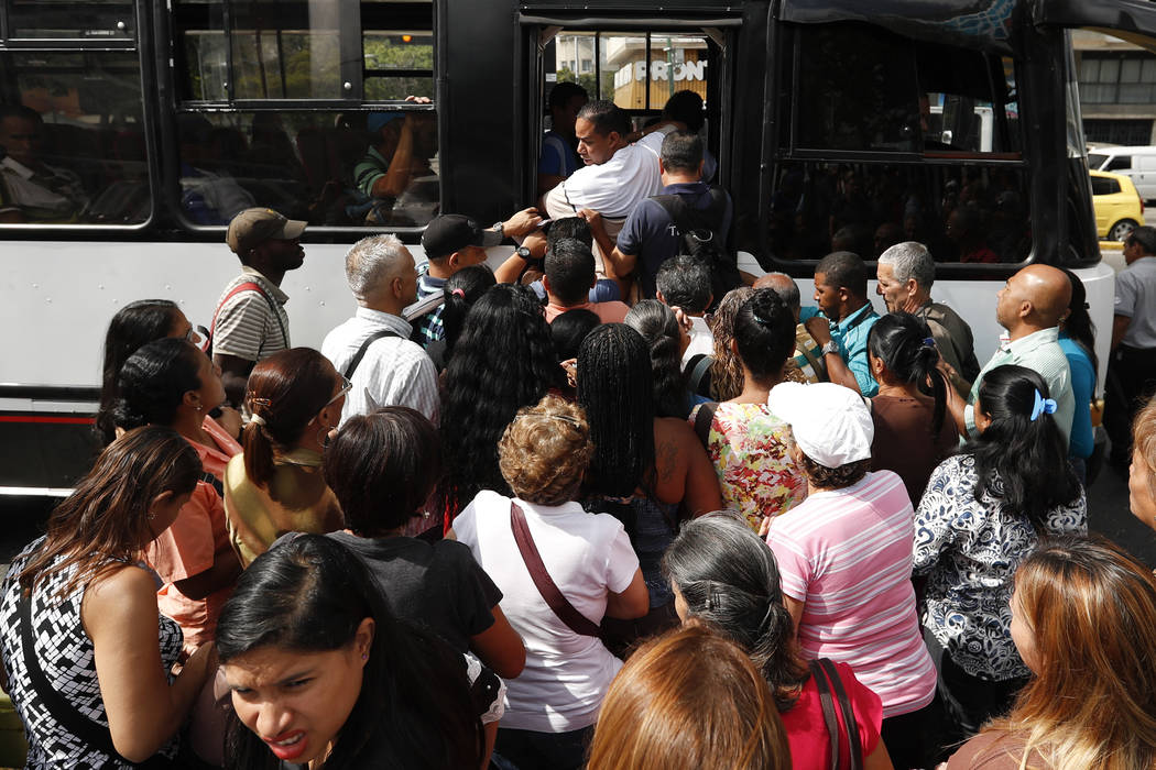 Passengers scramble to board a bus in Caracas, Venezuela, Thursday, March 14, 2019. With long lines at the stops of public transport and crowds of people at the entrance of some banking agencies, ...