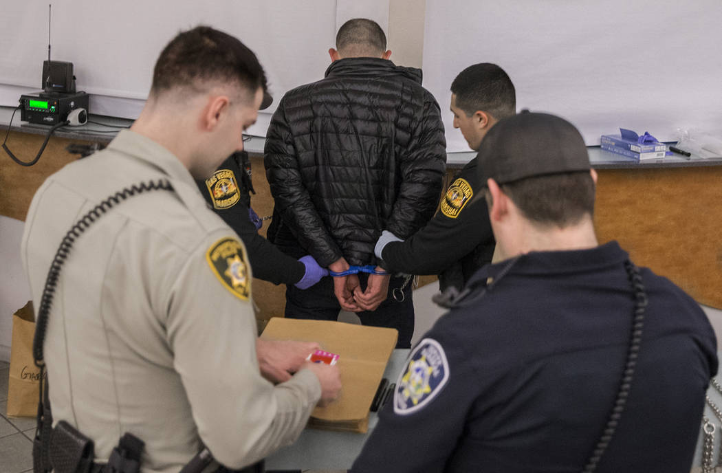 A suspected impaired driver, middle, is processed by Las Vegas Marshals at the Metro Traffic Bureau as part of a "DUI blitz" on Thursday, March 14, 2019, in Las Vegas. (Benjamin Hager Re ...