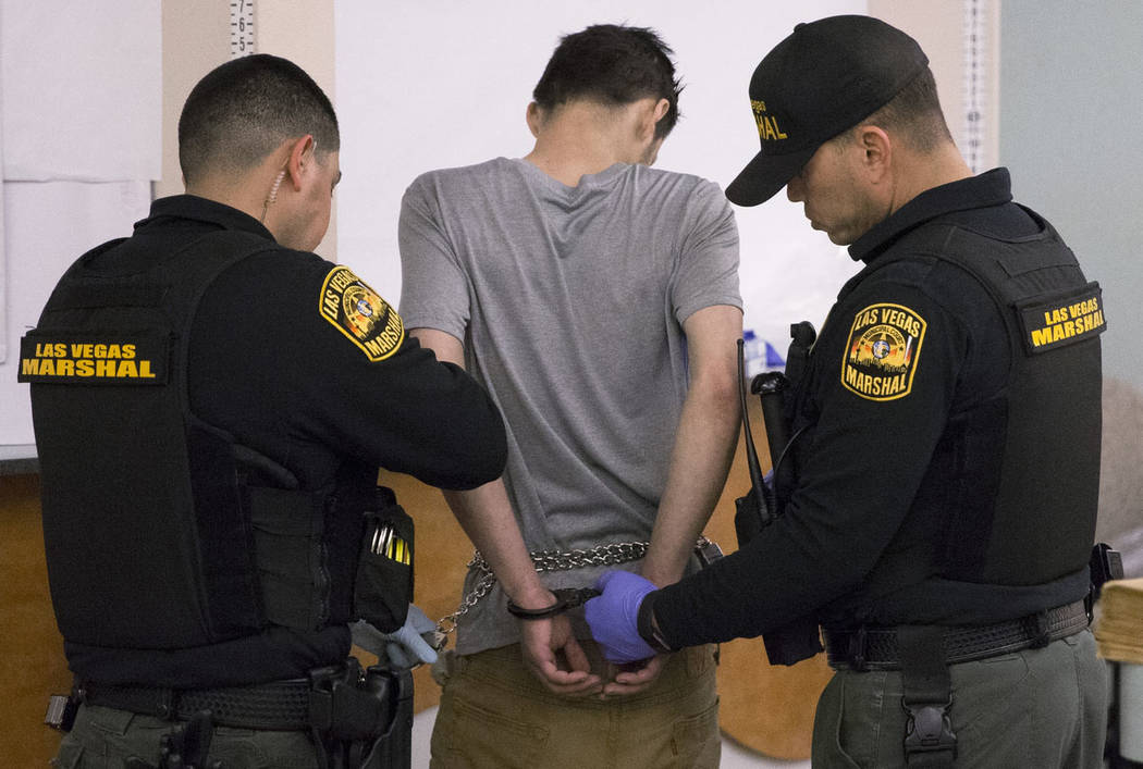 Marshal Johnny Patino, left, and Marshal David Reyes, right, process a suspected impaired driver at the Metro Traffic Bureau as part of a "DUI blitz" on Thursday, March 14, 2019, in Las ...
