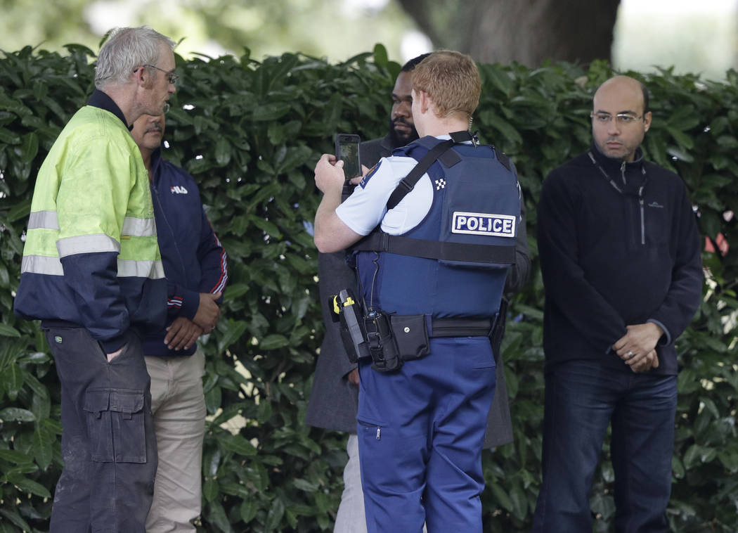 A police officer photographs witnesses near a mosque in central Christchurch, New Zealand, Friday, March 15, 2019. Multiple people were killed in mass shootings at two mosques full of people atten ...