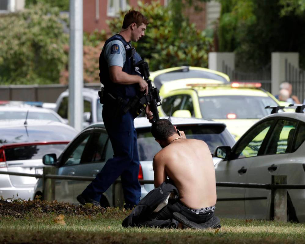 A man rests on the ground as he speaks on his mobile phone across the road from mosque in central Christchurch, New Zealand, Friday, March 15, 2019. (AP Photo/Mark Baker)