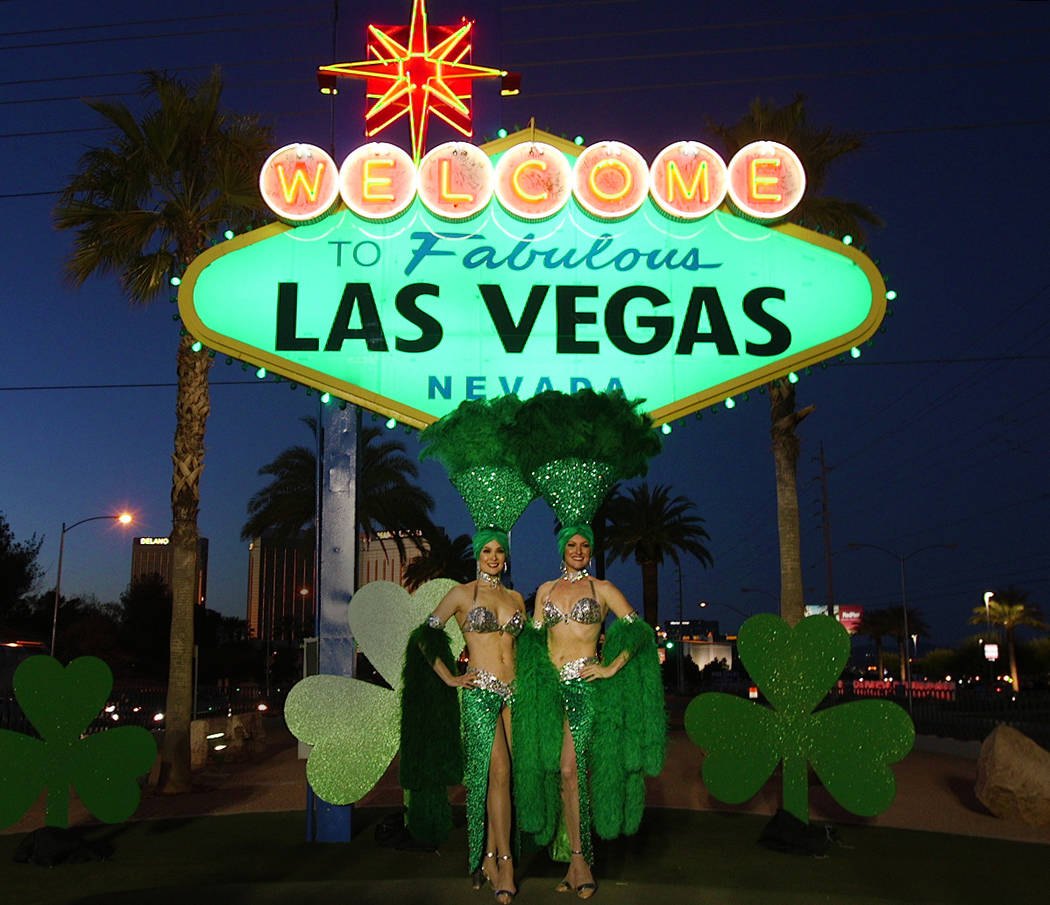 Showgirls pose in front of the "Welcome to Fabulous Las Vegas" sign on Thursday, March 14, 2019. The sign was lit green in celebration of St. Patrick's Day. (Mat Luschek/Las Vegas Review-Journal)