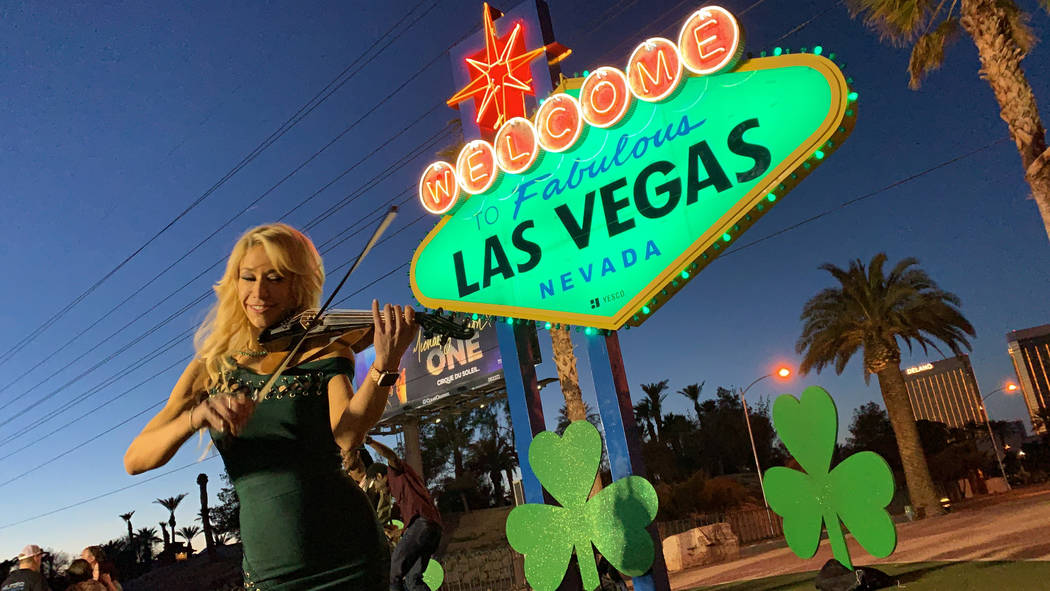 DJ/violinist Lydia Ansel plays the violin in front of the "Welcome to Fabulous Las Vegas" sign on Thursday, March 14, 2019. The sign was lit green in celebration of St. Patrick's Day. (Mat Luschek ...