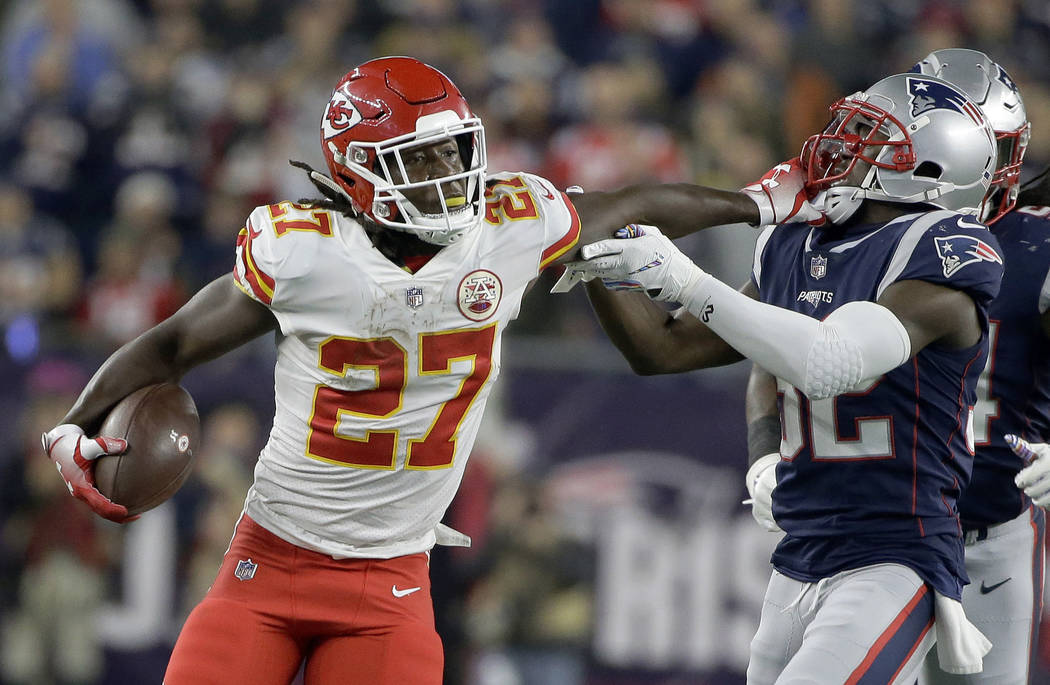 Kansas City Chiefs running back Kareem Hunt (27) gives a stiff arm to New England Patriots defensive back Devin McCourty (32) as he runs for yardage during the first half of an NFL football game, ...