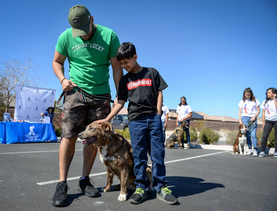 Veteran Sheldon Moniz, left, and his son Xavier Moniz, 11, from Las Vegas stand with their new dog Warrior as the Nevada Department of Corrections partners with the "Those Left Behind" F ...