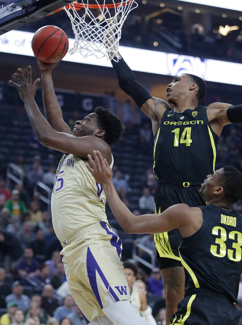 Washington's Noah Dickerson shoots around Oregon's Kenny Wooten (14) and Francis Okoro during the first half of an NCAA college basketball game in the final of the Pac-12 men's tournament Saturday ...
