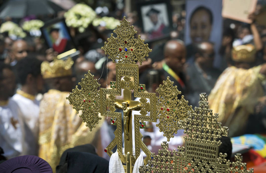 A crucifix is held by a priest at a mass funeral at the Holy Trinity Cathedral in Addis Ababa, Ethiopia Sunday, March 17, 2019. Thousands of Ethiopians have turned out to a mass funeral ceremony i ...