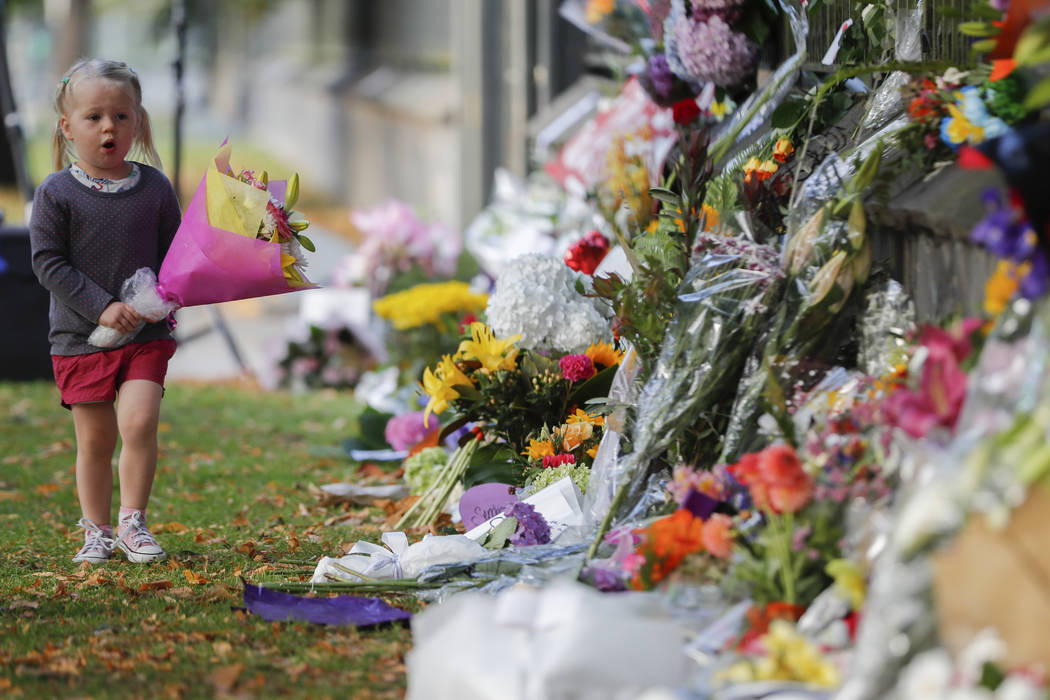 A girl walk to lay flowers on a wall at the Botanical Gardens in Christchurch, New Zealand, Sunday, March 17, 2019. New Zealand's stricken residents reached out to Muslims in their neighborhoods a ...