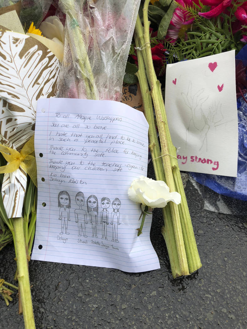 Signs and flowers are placed in Hagley Park near the Al Noor mosque, one of the mosque shooting sites in Christchurch, New Zealand, Sunday, March 17, 2019. An attack on a New Zealand mosque took ...