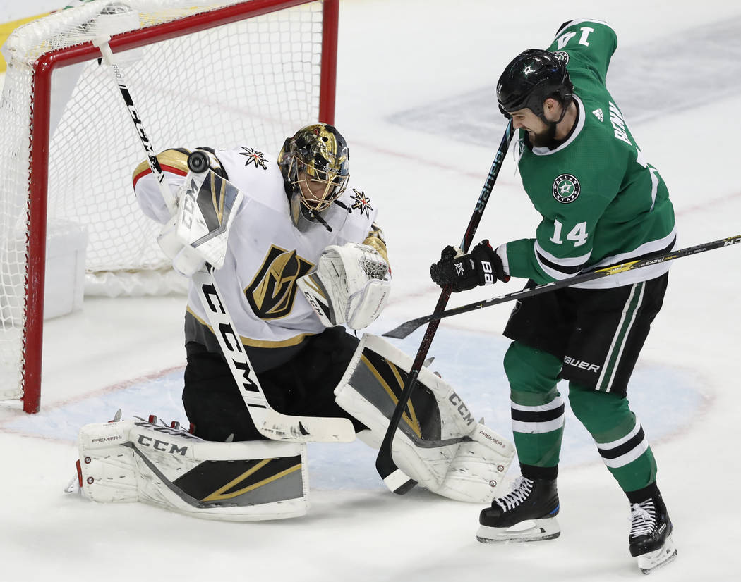 Vegas Golden Knights goaltender Marc-Andre Fleury (29) deflects a shot with his glove under pressure from Dallas Stars left wing Jamie Benn (14) in the third period of an NHL hockey game in Dallas ...
