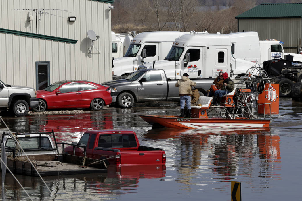 Gabe Schmidt, owner of Liquid Trucking, right, talks to Glenn Wyles, second right, as they survey by air boat flood damage from the flood waters of the Platte River, in Plattsmouth, Neb., Sunday, ...