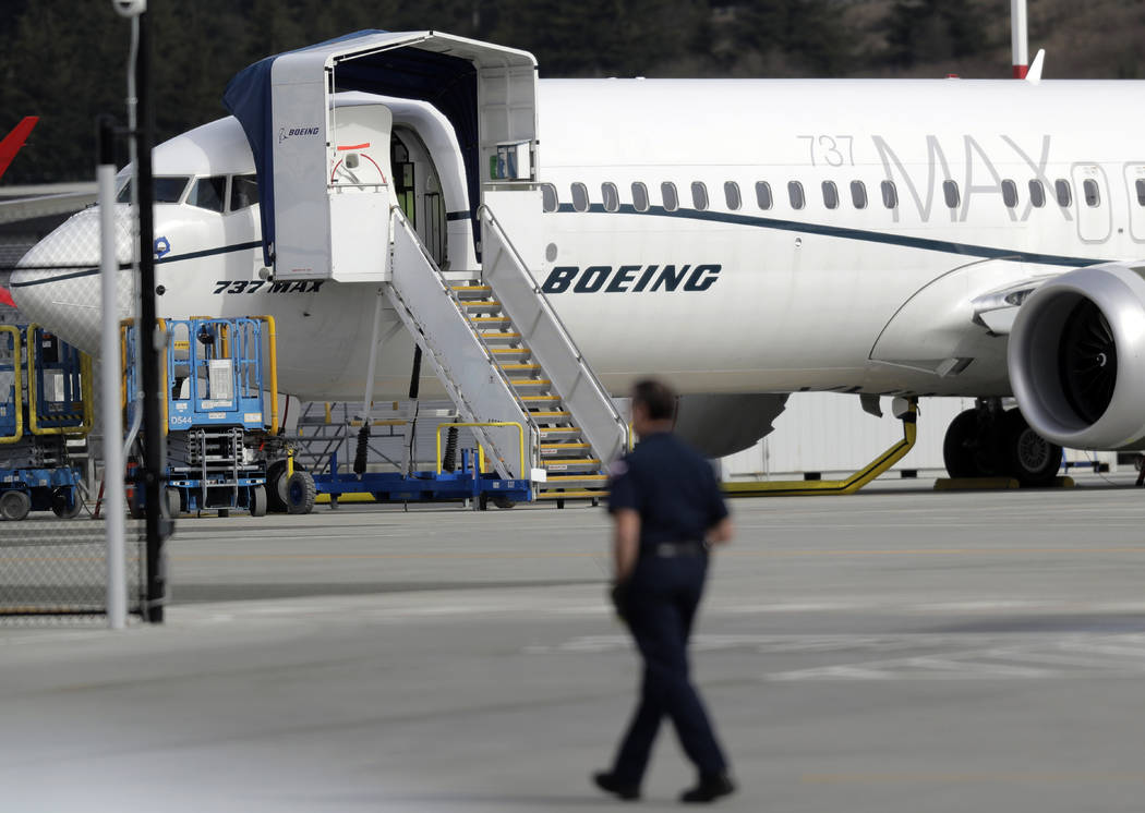 FILE- In this March 14, 2019, file photo a worker walks next to a Boeing 737 MAX 8 airplane parked at Boeing Field in Seattle. U.S. prosecutors are looking into the development of Boeing's 737 Max ...