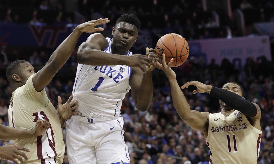 Duke's Zion Williamson, center, loses the ball as he is trapped by Florida State's David Nichols, right, and Raiquan Gray, left, during the first half of the NCAA college basketball championship g ...