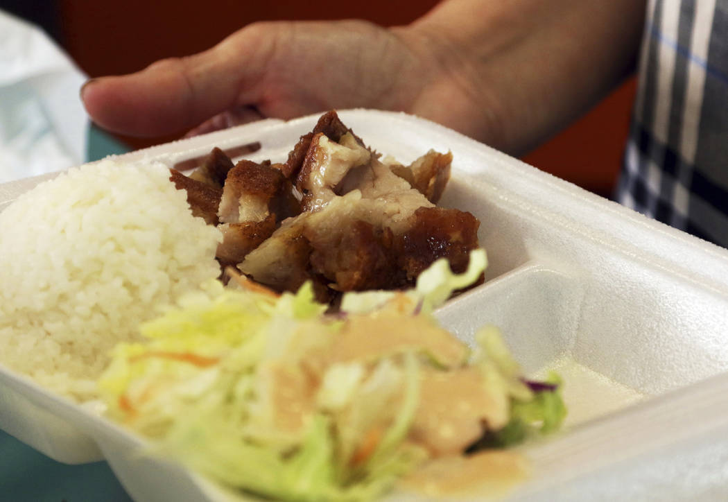 In this Thursday, March 14, 2019 photo, Belinda Lau, manager of the Wiki Wiki Drive Inn takeout restaurant in Honolulu, holds a polystyrene foam box containing an order of roast pork, rice and sal ...