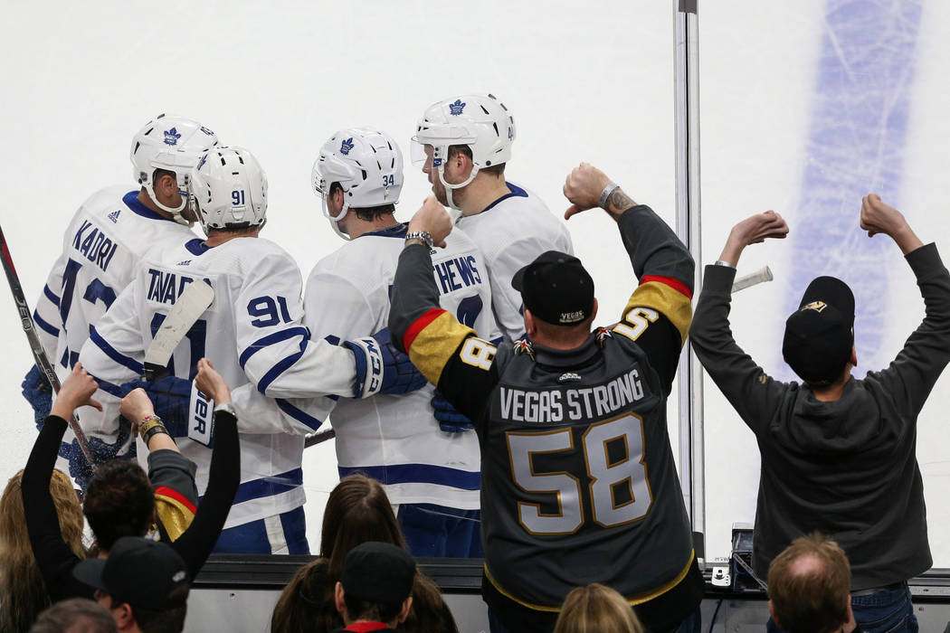 Vegas Golden Knights fans hold up thumbs down as the Toronto Maple Leafs celebrate after Toronto Maple Leafs center Auston Matthews (26) scores a goal against the Vegas Golden Knights during ...