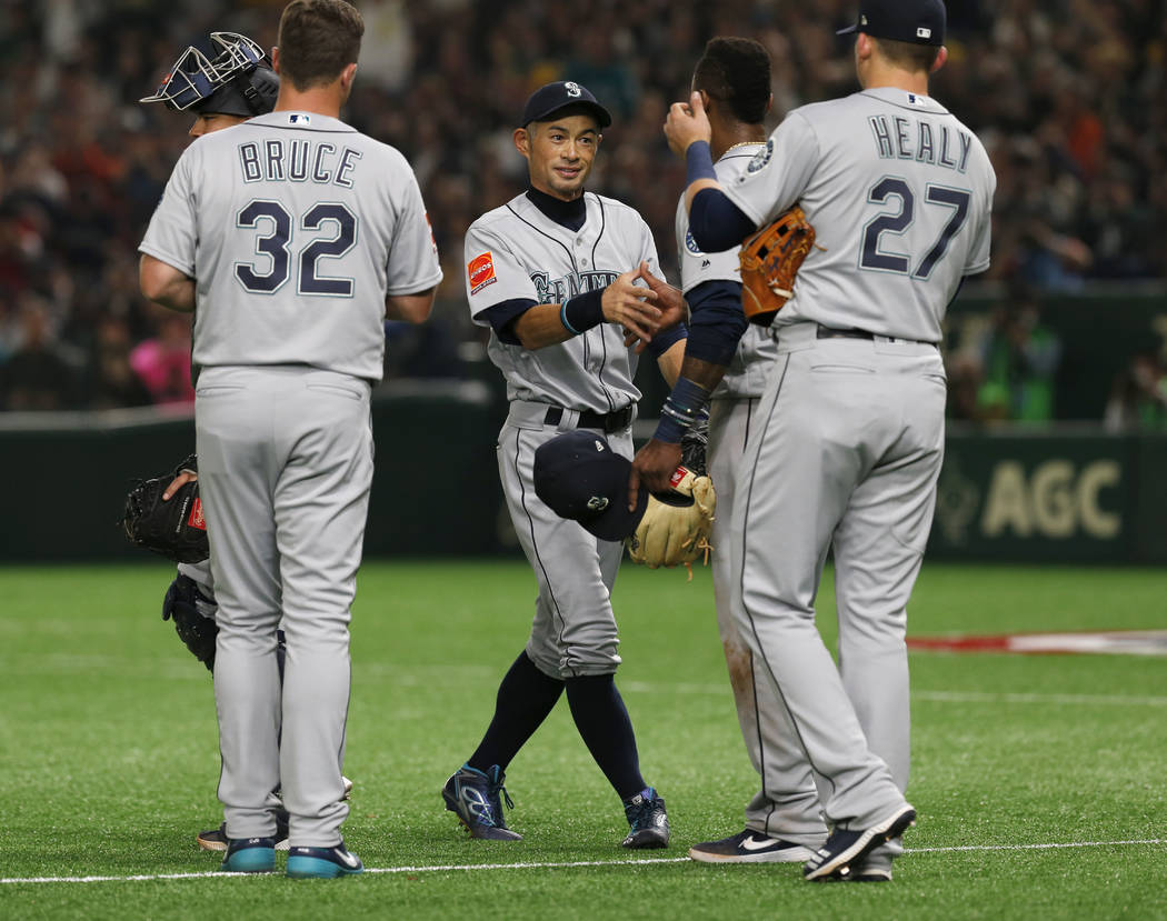Seattle Mariners right fielder Ichiro Suzuki, center, talks to his teammates while leaving the field for defense substitution in the fourth inning of Game 1 of the Major League opening baseball se ...