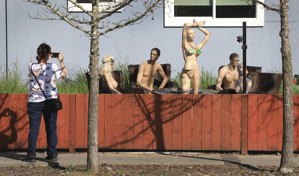 In this photo taken Monday, March 18, 2019, a woman stops to photograph a display of mannequins in Santa Rosa, Calif. Homeowner Jason Winduce set up the display, after a neighbor in the area compl ...
