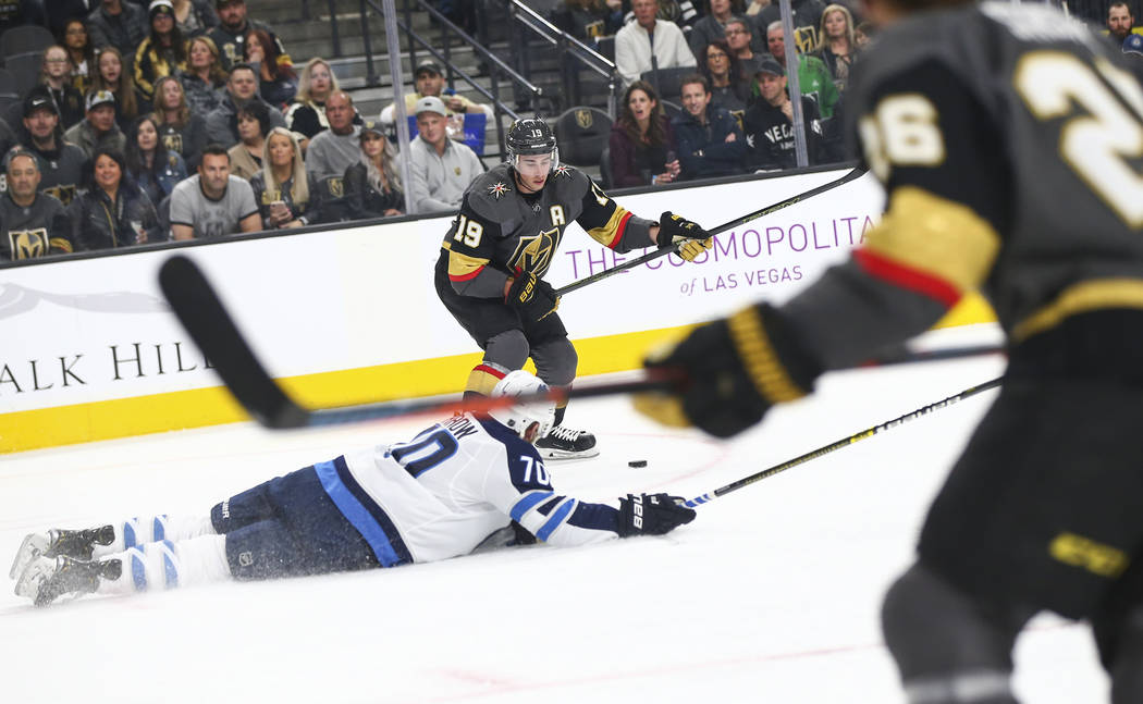 Winnipeg Jets defenseman Joe Morrow (70) falls to the ice as Golden Knights right wing Reilly Smith (19) lines up the puck to score the team's second goal against the Jets during the first period ...
