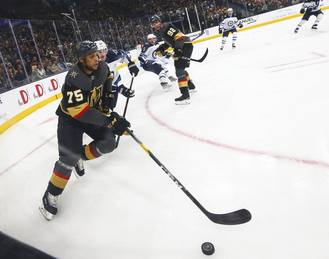 Golden Knights right wing Ryan Reaves (75) moves the puck past Winnipeg Jets defenseman Tyler Myers (57) during the first period of an NHL hockey game at T-Mobile Arena in Las Vegas on Thursday, M ...