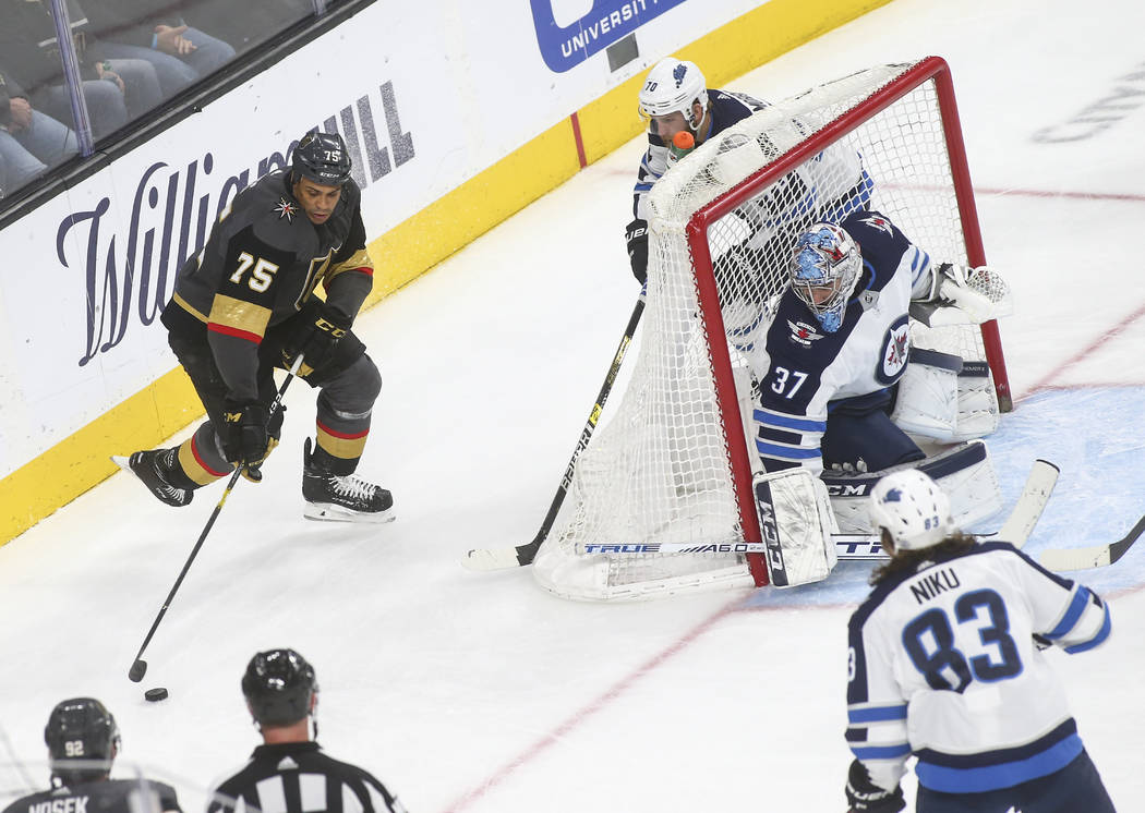 Golden Knights right wing Ryan Reaves (75) moves the puck around Winnipeg Jets defenseman Joe Morrow (70) and goaltender Connor Hellebuyck (37) during the third period of an NHL hockey game at T-M ...