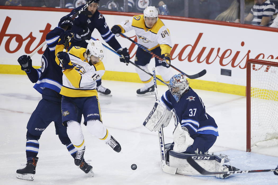 Winnipeg Jets goaltender Connor Hellebuyck (37) keeps his eye on the puck as Nashville Predators' Craig Smith (15) tips it during the first period of an NHL hockey game, Saturday, March 23, 2019 i ...
