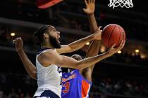 Nevada forward Caleb Martin drives to the basket past Florida center Kevarrius Hayes, rear, during a first round men's college basketball game in the NCAA Tournament, Thursday, March 21, 2019, in ...