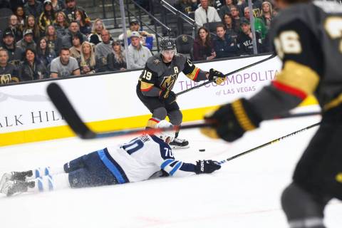 Winnipeg Jets defenseman Joe Morrow (70) falls to the ice as Golden Knights right wing Reilly Smith (19) lines up the puck to score the team's second goal against the Jets during the first period ...