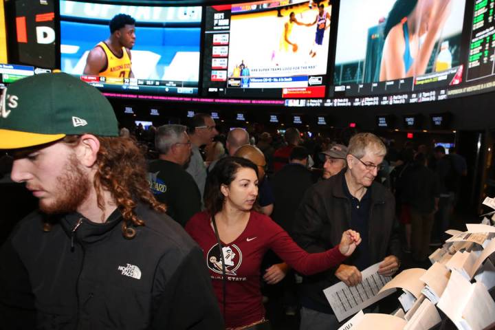 Fans, including Ivette Abramyan, center, of Jacksonville, Fla,., lined up to place their bets during the first day of the NCAA basketball tournament at the Westgate sports book in Las Vegas on Thu ...