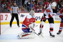 Washington Capitals goaltender Braden Holtby (70) tries to corral the puck, next to New Jersey Devils center Blake Coleman (20) during the first period of an NHL hockey game Friday, March 8, 2019, ...