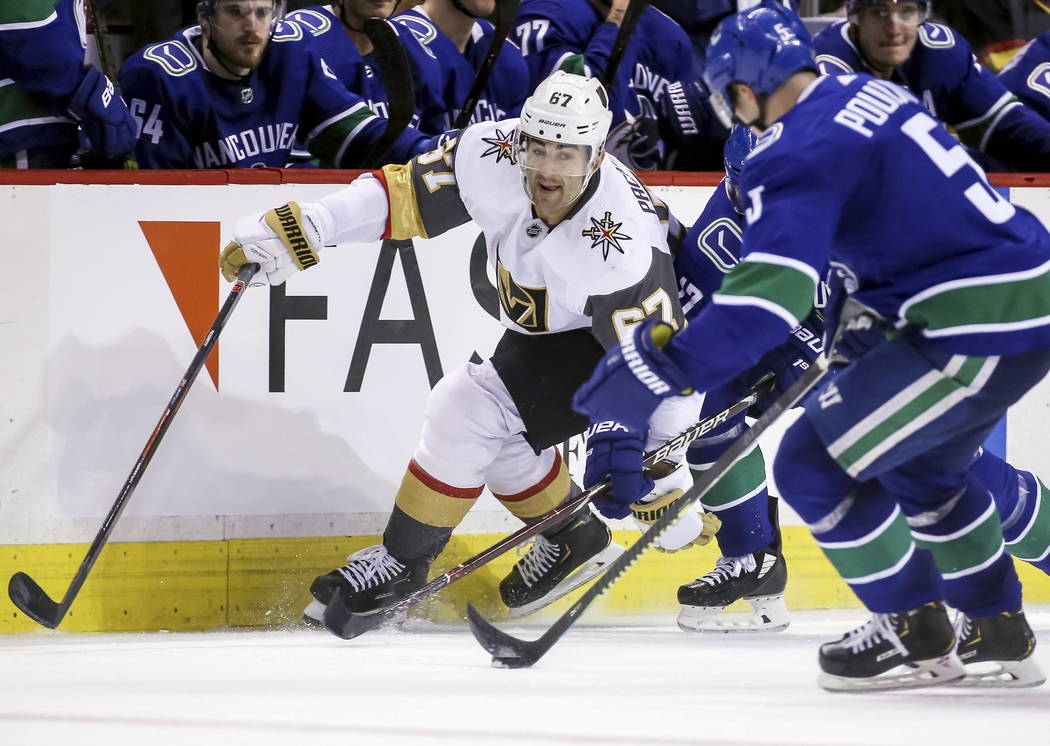 Vegas Golden Knights' Max Pacioretty (67) fights for the puck against Vancouver Canucks' Derrick Pouliot (5) during the second period of an NHL hockey game in Vancouver, British Columbia, Saturday ...