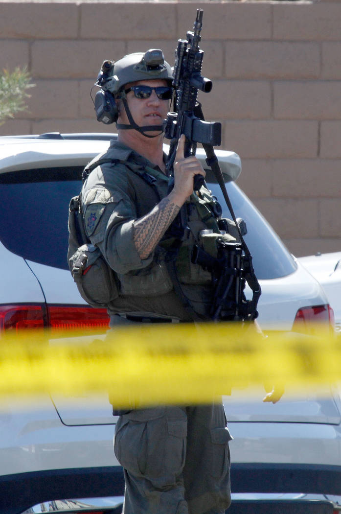 A Metropolitan Police Department SWAT team member stands with a gun during a barricade situation near Grand Teton and Durango in the northwest area of the Las Vegas valley, Saturday, March 23, 20 ...