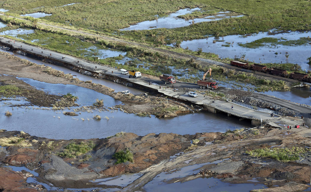 An aerial photo shows local residents walk on a damaged road following the devastating Tropical Cyclone Idai in Beira, Mozambique, Saturday, March 23, 2019. A second week has begun with efforts to ...