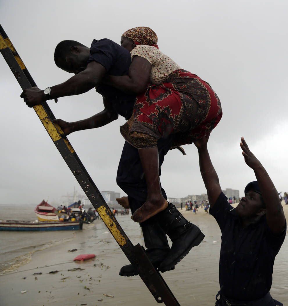 An elderly woman is assisted disembark from a boat after being rescued from a flooded area of Buzi district, 200km outside Beira, Mozambique, Saturday, March 23, 2019. A second week has begun with ...