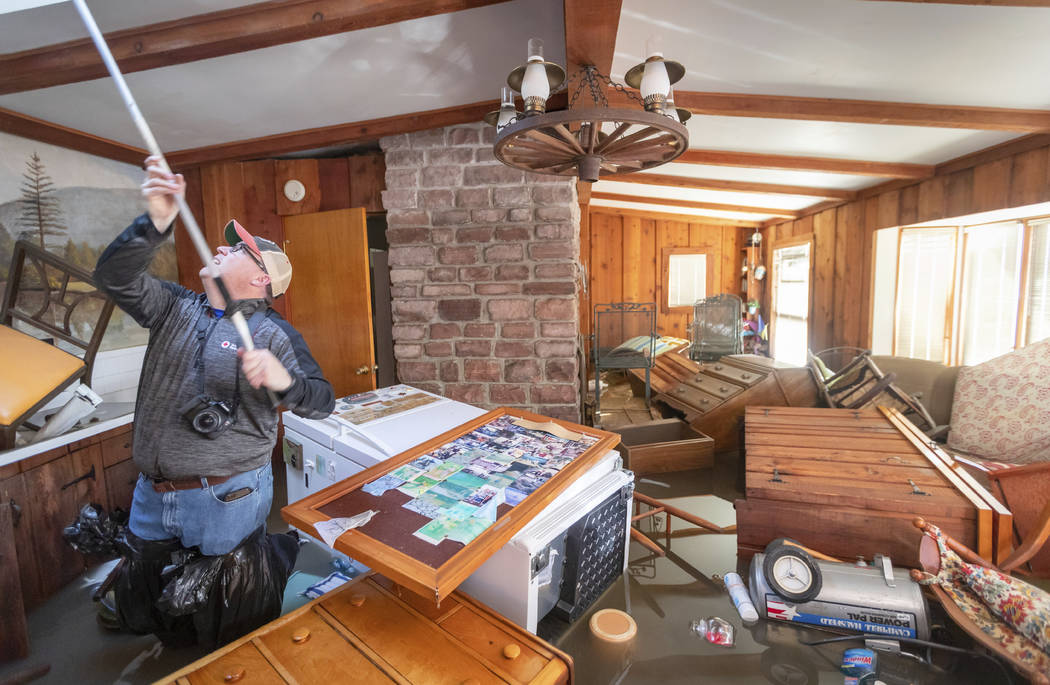 Steve O'Donnell works to open a skylight while standing in floodwaters inside a home Friday, March 22, 2019, in Bellevue, Neb. Flooding in Nebraska has caused an estimated $1.4 billion in damage. ...