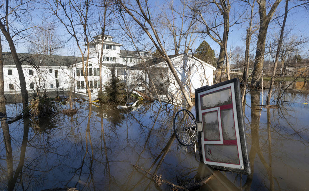 A wayward basketball hoop is seen behind a flooded home Friday, March 22, 2019, in Bellevue, Neb. Flooding in Nebraska has caused an estimated $1.4 billion in damage. The state received Trump's fe ...