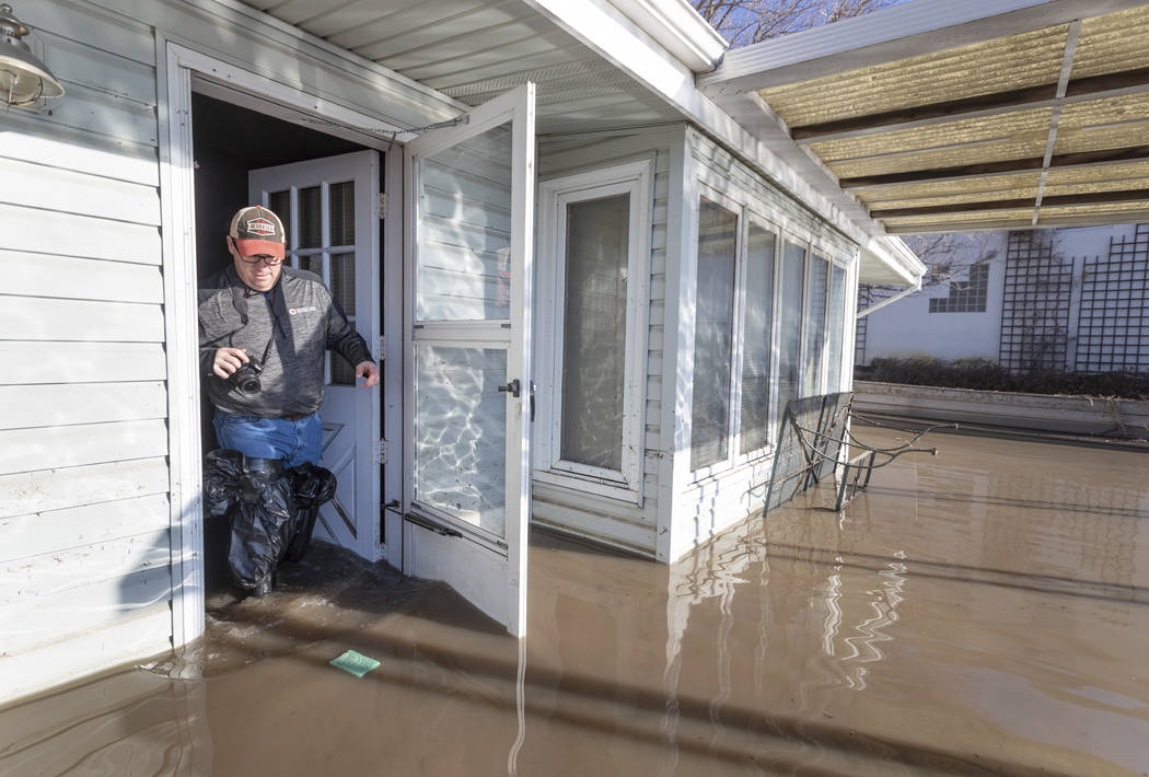 Steve O'Donnell exits his parent's flooded lake house in the Hanson's Lake area Friday, March 22, 2019, in Bellevue, Neb. Flooding in Nebraska has caused an estimated $1.4 billion in damage. The s ...