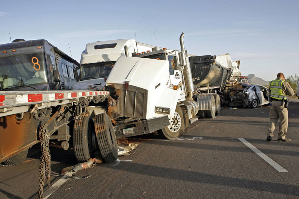In this Oct. 29, 2013, file photo, Arizona Department of Public Safety officers investigate a multiple fatality accident involving six semi tractor-trailers and 19 other vehicles after a dust stor ...