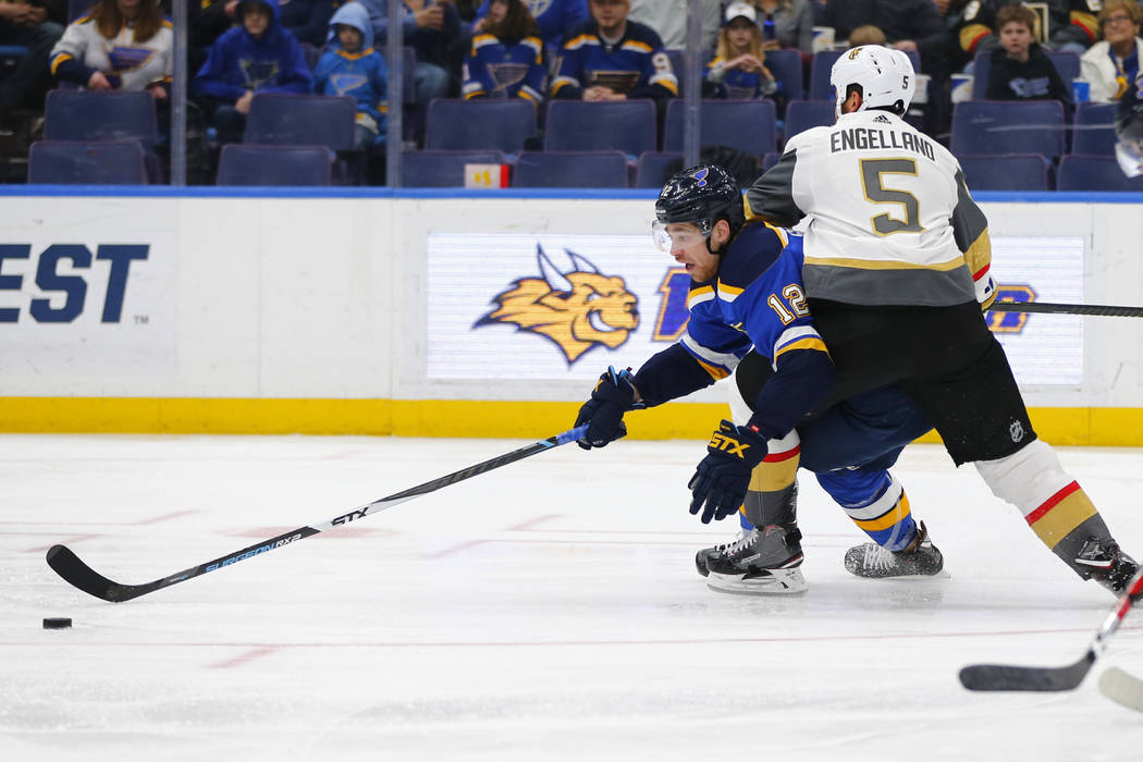 St. Louis Blues' Zach Sanford (12) attempts to maintain control of the puck against Vegas Golden Knights' Deryk Engelland (5) during the second period of an NHL hockey game Monday, March 25, 2019, ...