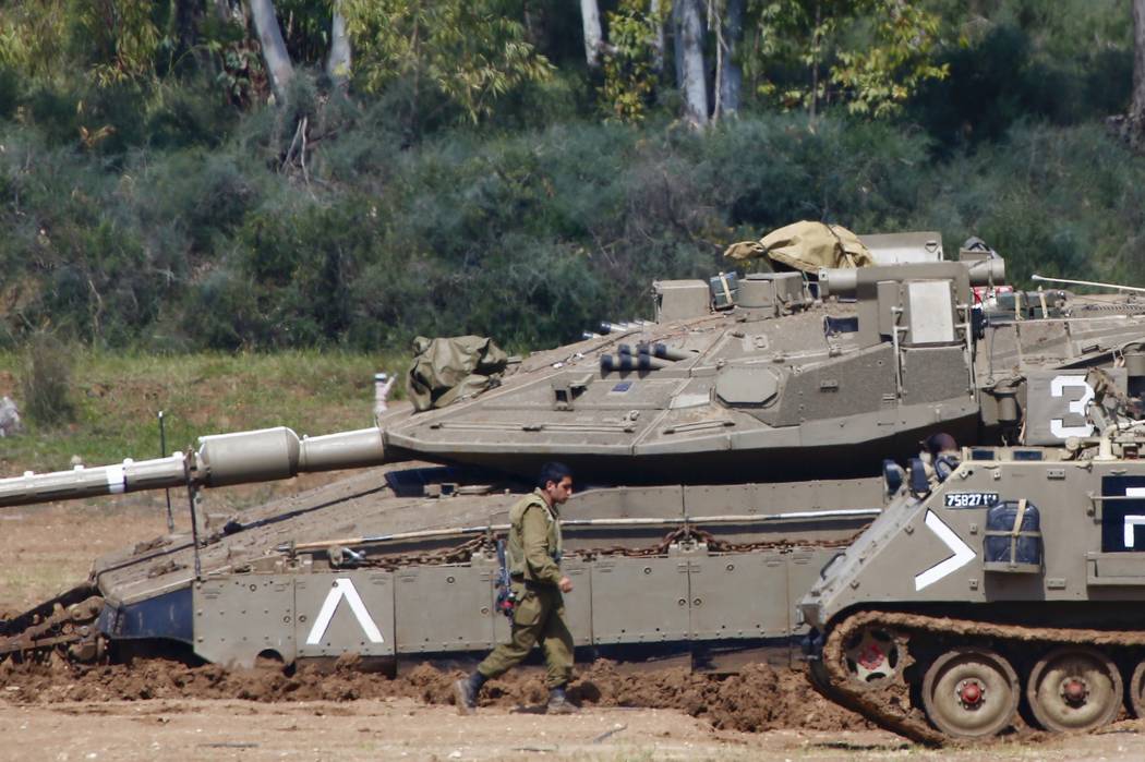 Israeli soldiers work next to their tanks near the Israel Gaza border, Israel, Tuesday, March 26, 2019. A tense quiet took hold on Tuesday morning after a night of heavy fire as Israeli aircraft b ...