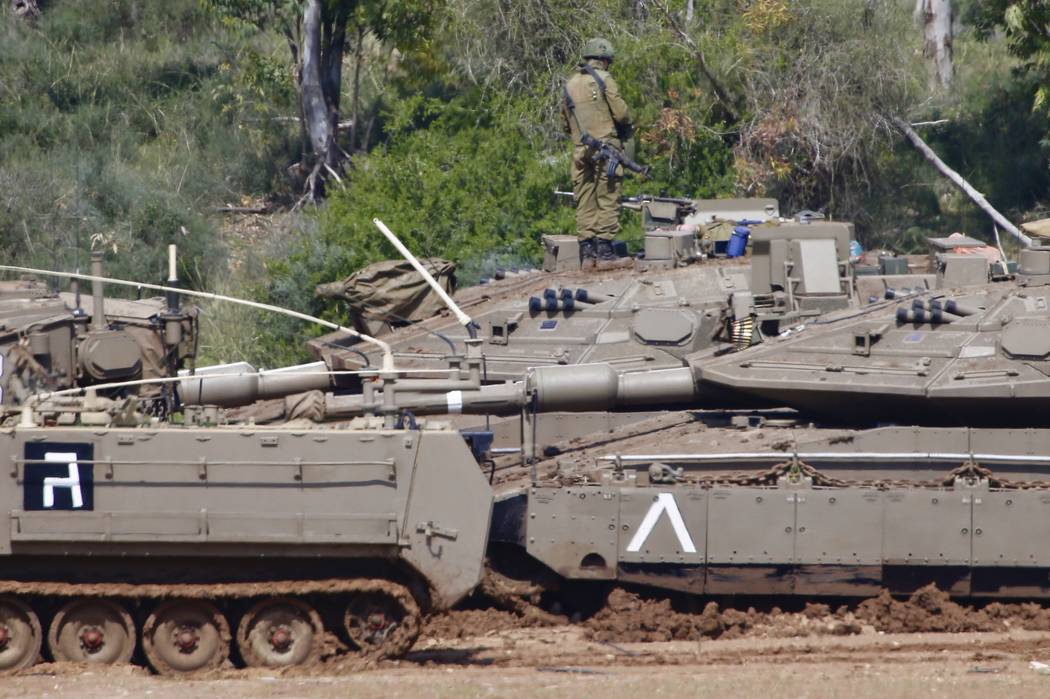 Israeli soldiers work next to their tanks near the Israel Gaza border, Israel, Tuesday, March 26, 2019. A tense quiet took hold on Tuesday morning after a night of heavy fire as Israeli aircraft b ...