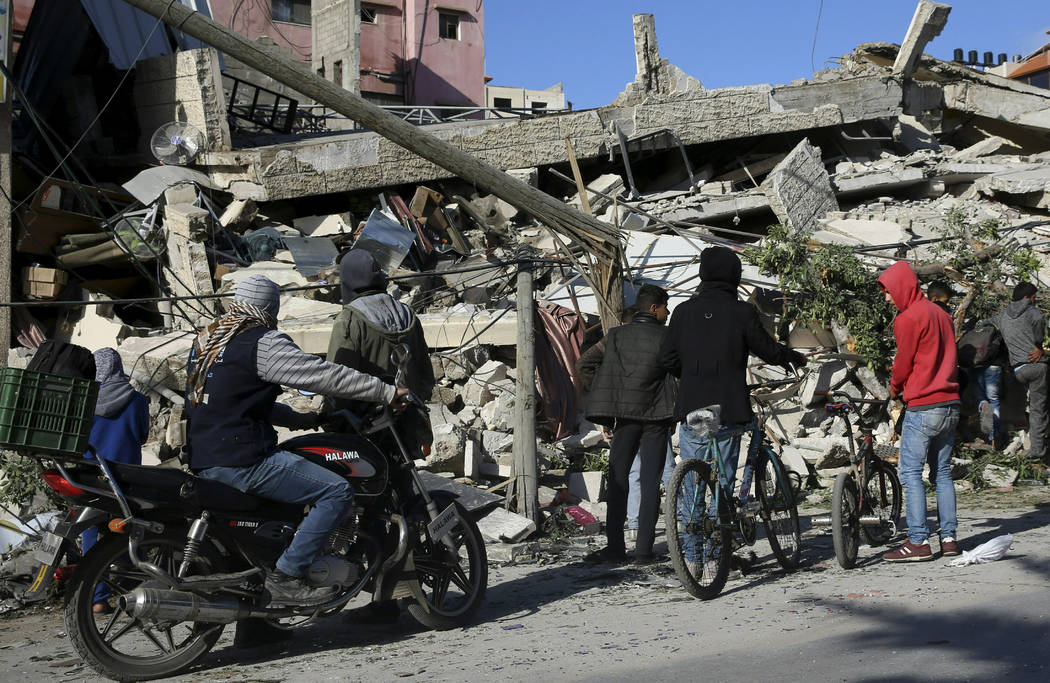Residents inspect the damage of a destroyed multi-story building of Hamas-affiliated insurance company, in Gaza City, Tuesday, March 26, 2019. A tense quiet took hold Tuesday morning after a night ...