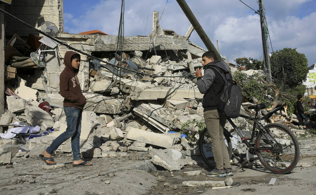 Residents look at the damage of the destroyed multi-story building of Hamas-affiliated insurance company, in Gaza City, Tuesday, March 26, 2019. A tense quiet took hold Tuesday morning after a nig ...