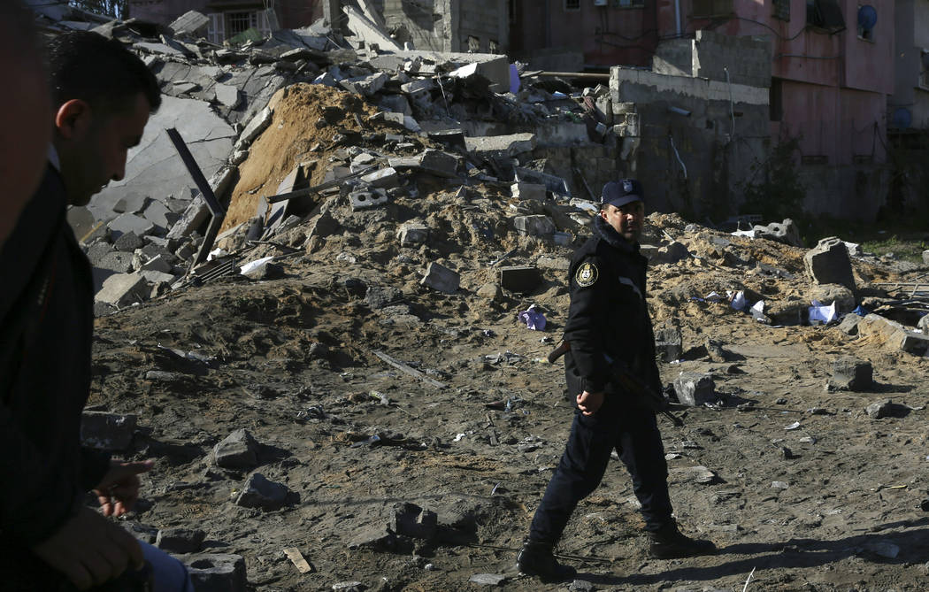 A Hamas police officer inspects the damage of the destroyed multi-story building of Hamas-affiliated insurance company, in Gaza City, Tuesday, March 26, 2019. A tense quiet took hold Tuesday morni ...