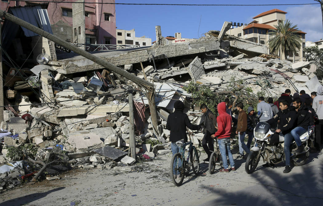 Residents inspect the damage of the destroyed multi-story building of Hamas-affiliated insurance company, in Gaza City, Tuesday, March 26, 2019. A tense quiet took hold Tuesday morning after a nig ...