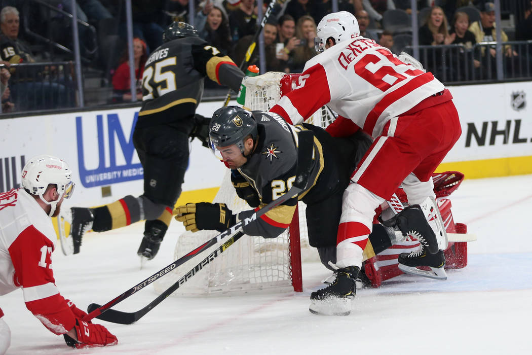 Vegas Golden Knights left wing William Carrier (28) is taken down by Detroit Red Wings defensem ...