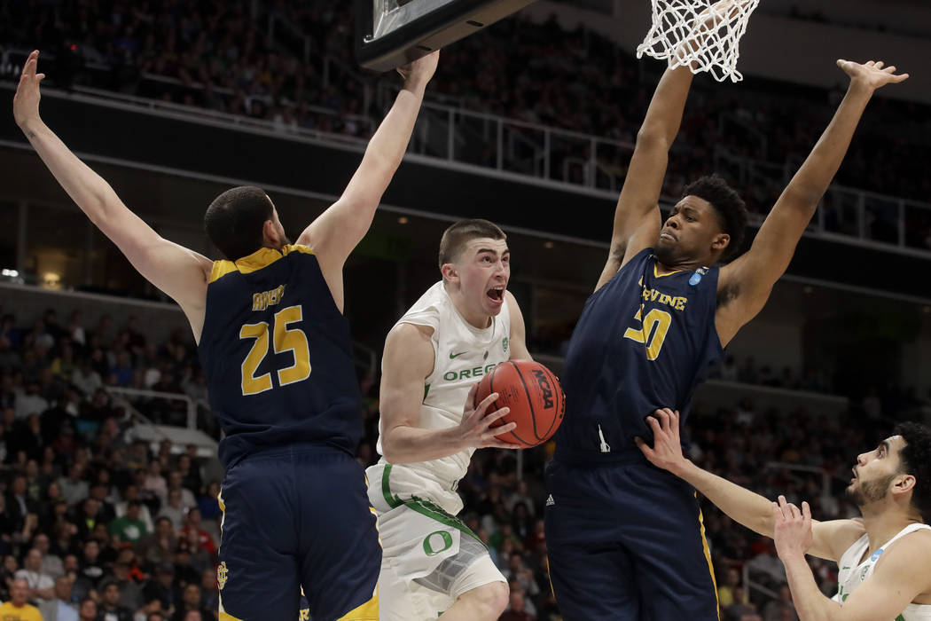 Oregon guard Payton Pritchard, middle, drives to the basket between UC Irvine guard Spencer Riv ...