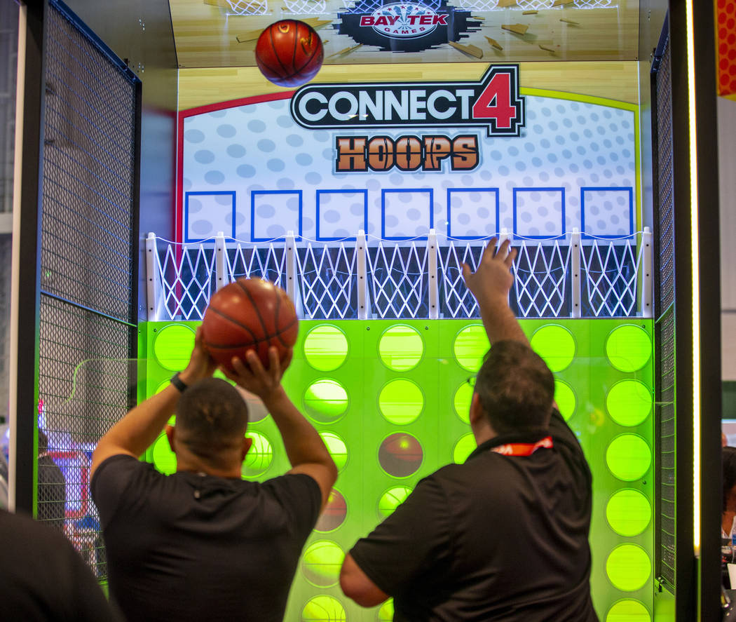Attendees shoot baskets in a Connect 4 Hoops game during the the Amusement Expo at the Las Vega ...