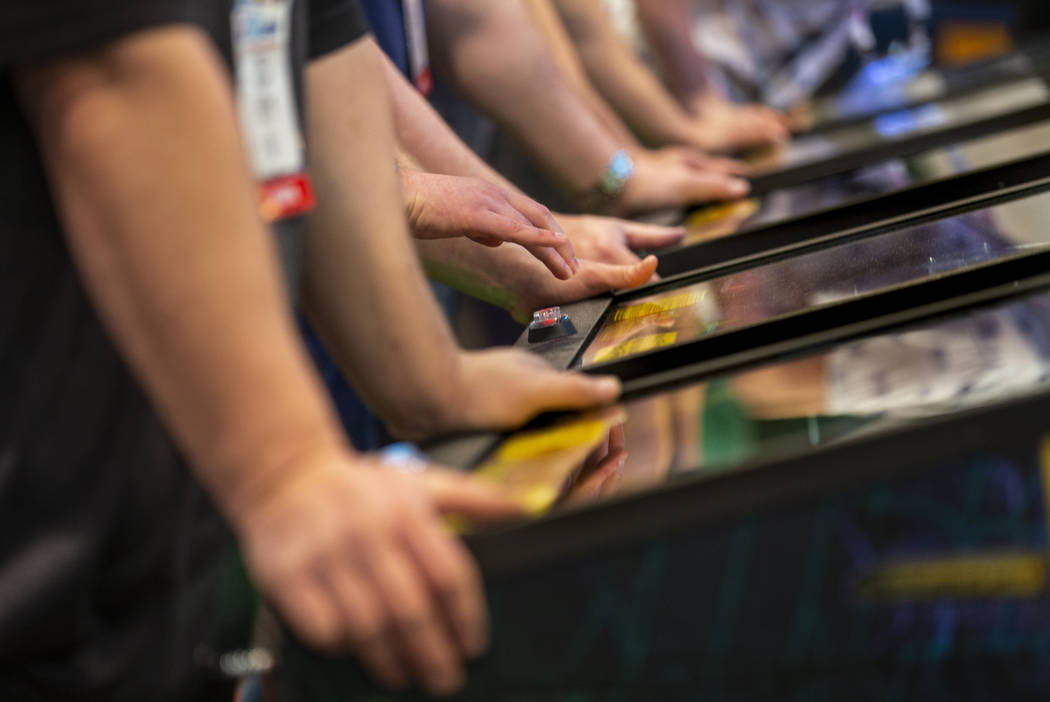 Attendees play pinball during the the Amusement Expo at the Las Vegas Convention Center on Wedn ...