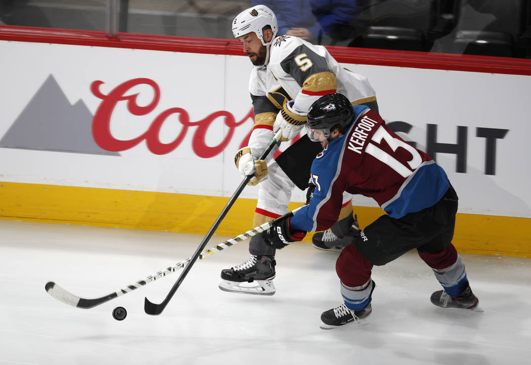 Vegas Golden Knights defenseman Deryk Engelland, back, passes the puck past Colorado Avalanche ...